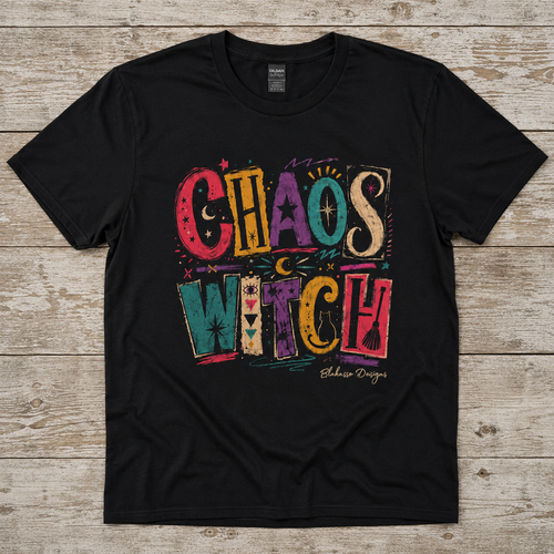 Black Chaos Witch T-shirt displayed on a weathered wood surface with colorful distressed lettering, celestial symbols, and eclectic witchy details.