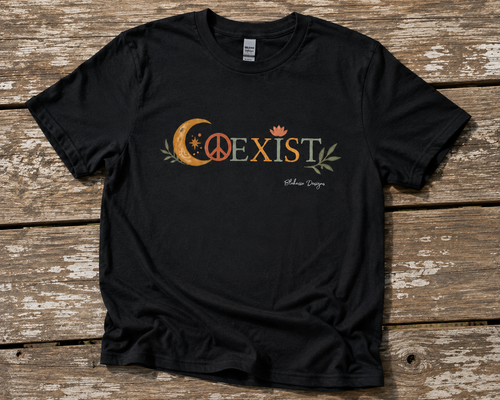 Black COEXIST unisex T-shirt displayed on a weathered wood surface with crescent moon, peace sign, lotus, and botanical artwork.
