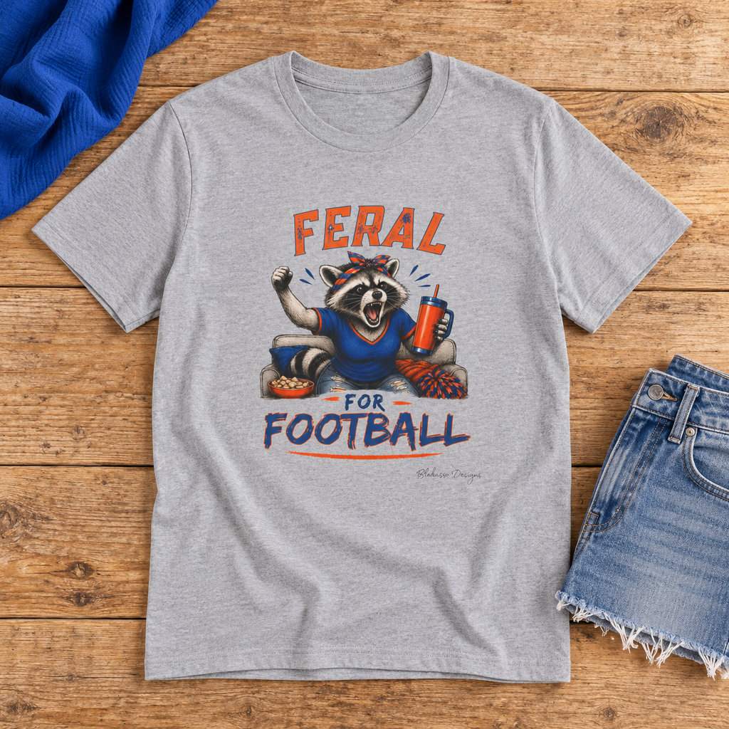 Gray Feral for Football shirt featuring a spirited raccoon design in orange and blue beside denim shorts.