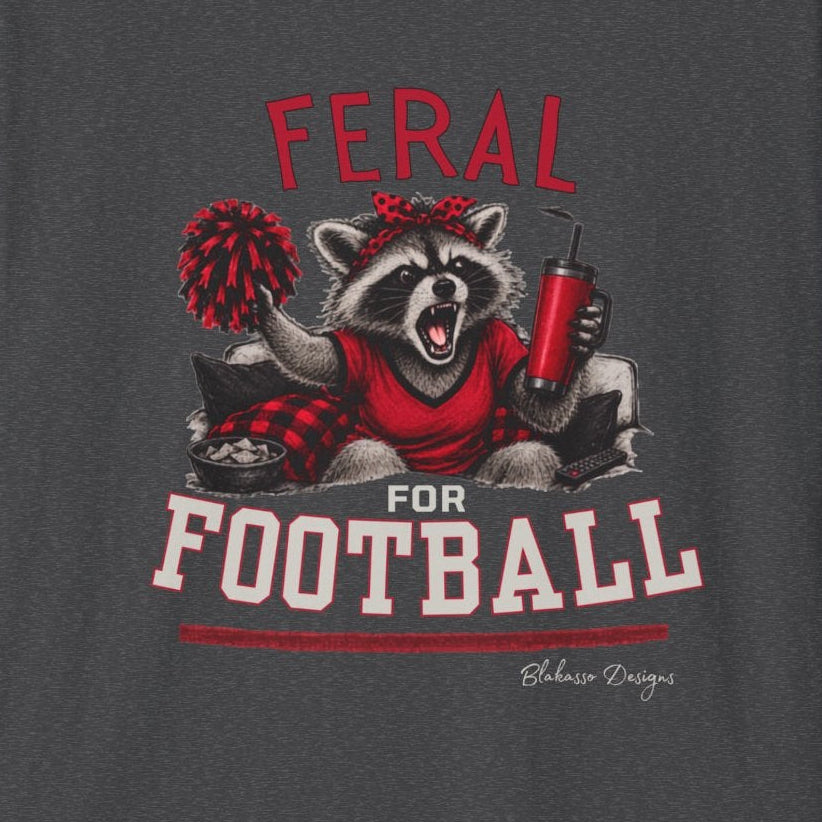Close up of Feral for Football Georgia raccoon shirt design in red, white, black, and graphite style on a dark heather T shirt.