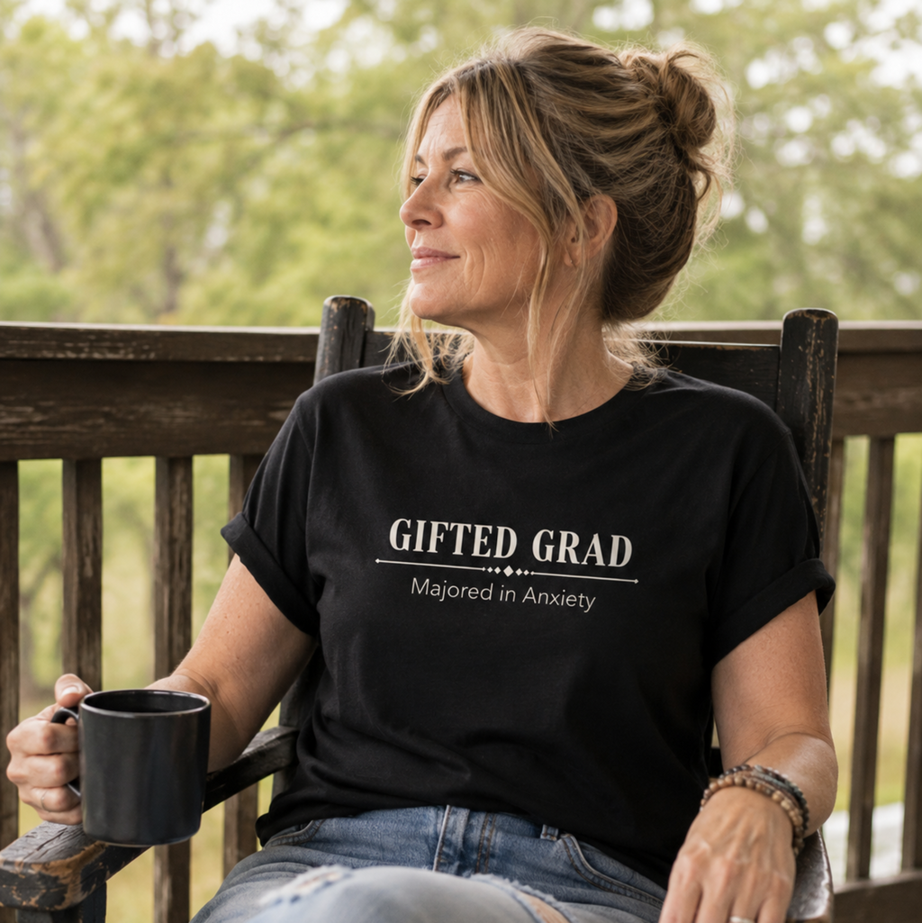 Woman wearing a black Gifted Grad Majored in Anxiety shirt while relaxing outdoors.