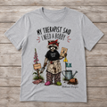 Sport Grey unisex T-shirt featuring a raccoon gardener with poison garden details and the text “My Therapist Said I Need a Hobby.”