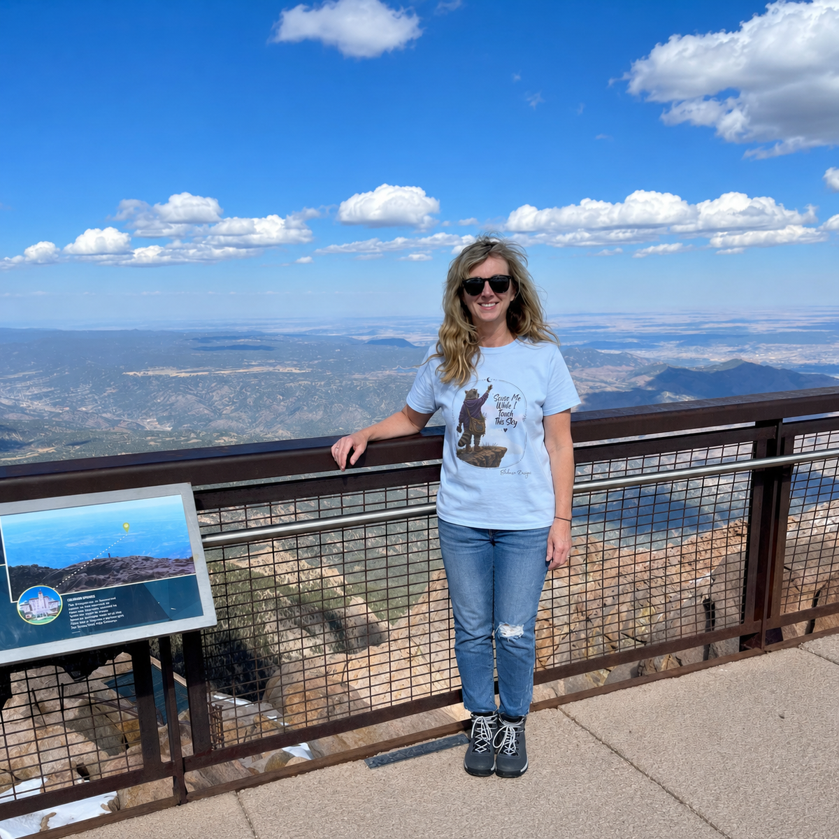 Woman wearing ’Scuse Me While I Touch This Sky Lynette raccoon graphic tee at a mountain overlook