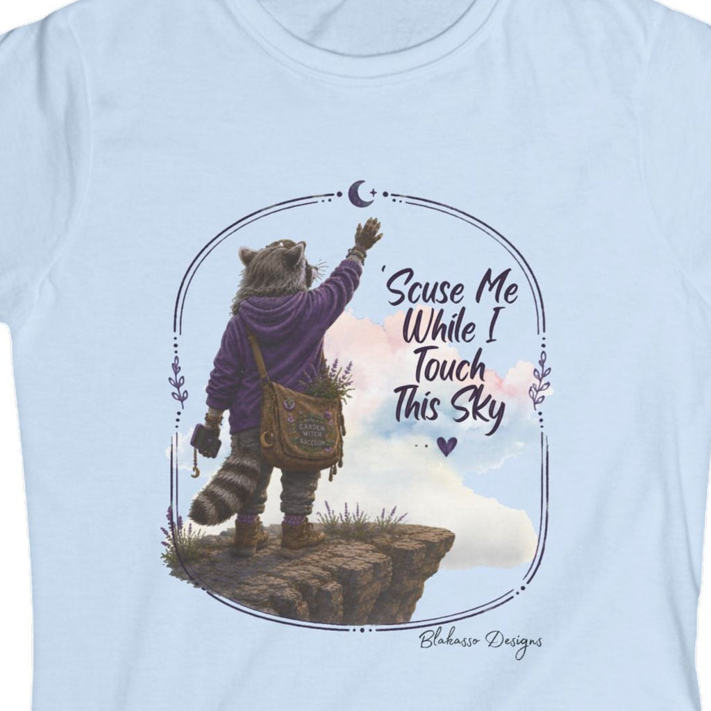 Close view of Lynette the raccoon standing on a rocky overlook and reaching toward the moon beneath the words Scuse Me While I Touch This Sky.