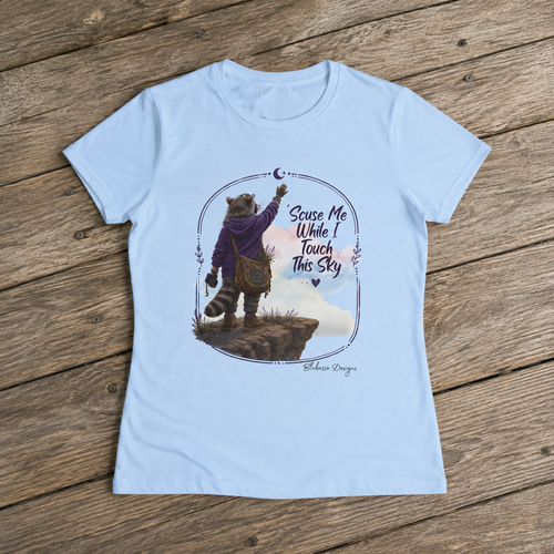 Light blue women’s T-shirt featuring Lynette the raccoon reaching toward the moon beneath the words Scuse Me While I Touch This Sky.
