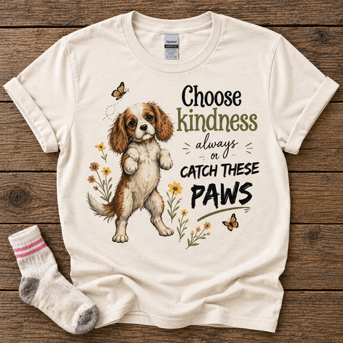 Natural T-shirt featuring the Choose Kindness Always or Catch These Paws Cavalier puppy design, styled with a stolen sock.