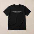 Black unisex tee laid flat on a warm neutral surface featuring the High Functioning Low Tolerance text design across the chest.