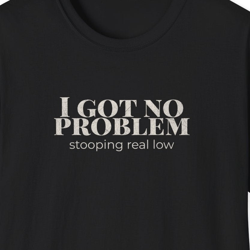 Close up of the distressed typography reading "I Got No Problem Stooping Real Low" on a black graphic tee.