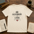 Natural Overthinking Is My Cardio graphic tee with rough hand drawn lettering, tangled thought cloud, sketch marks, stars, and red heart.