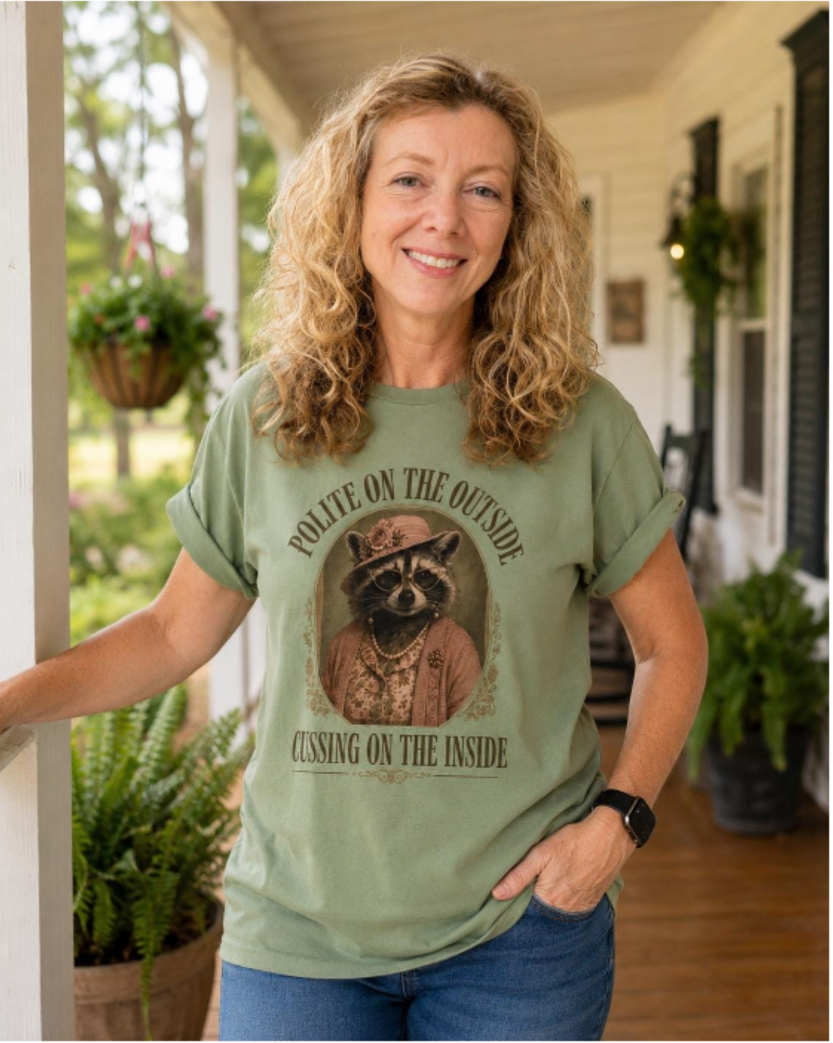 Woman wearing a sage “Polite on the Outside, Cussing on the Inside” Miss Cordelia raccoon graphic tee.
