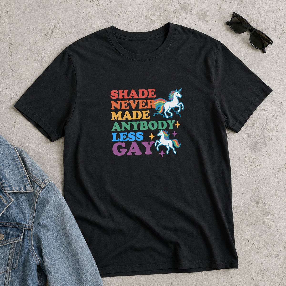 Black unisex graphic tee with rainbow lettering, colorful unicorns, and the words “Shade Never Made Anybody Less Gay.”