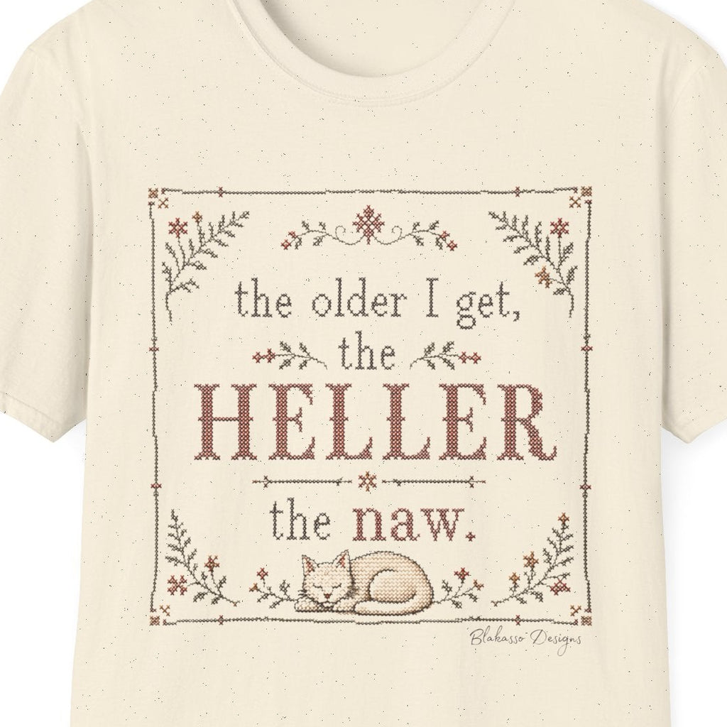 Close-up of The Older I Get, the Heller the Naw design showing the cross stitch inspired floral details, decorative border, lettering, and cat illustration.