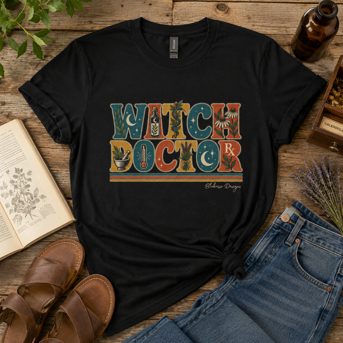 Black crew neck T-shirt featuring the retro Witch Doctor design with botanical, apothecary, celestial and vintage medical details.
